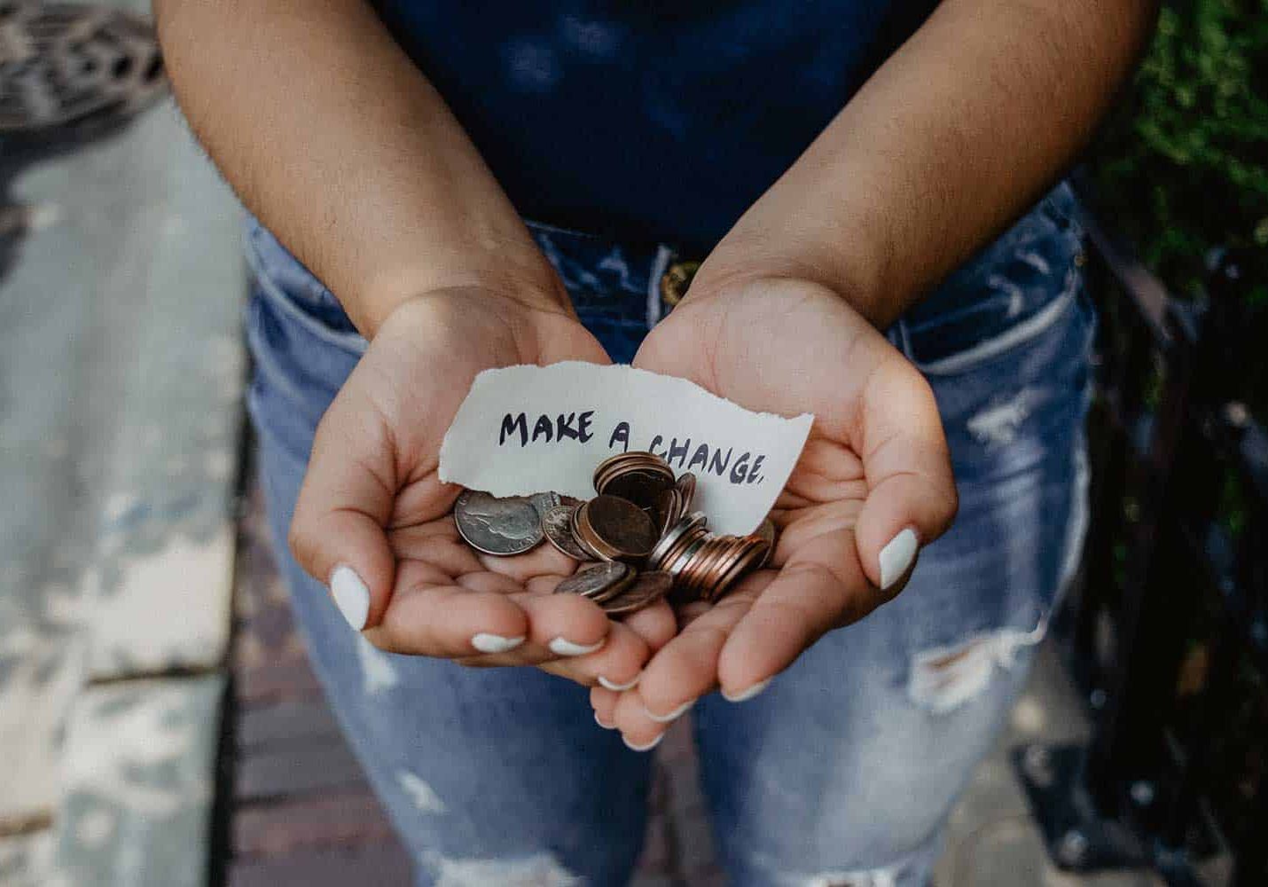 hands holding money with a sign that says make a change